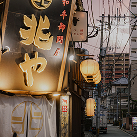 夕暮れ時の路地裏。提灯の温かい灯りが灯る居酒屋や電柱が並び、どこか懐かしく情緒溢れる街並みの風景。