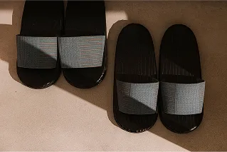 玄関に並べられた、シックな黒のソールにグレーの織生地をあわせたルームスリッパ。
