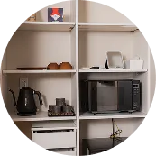 キッチン家電が整った共用スペース。電子レンジやポットなどが並ぶ棚。