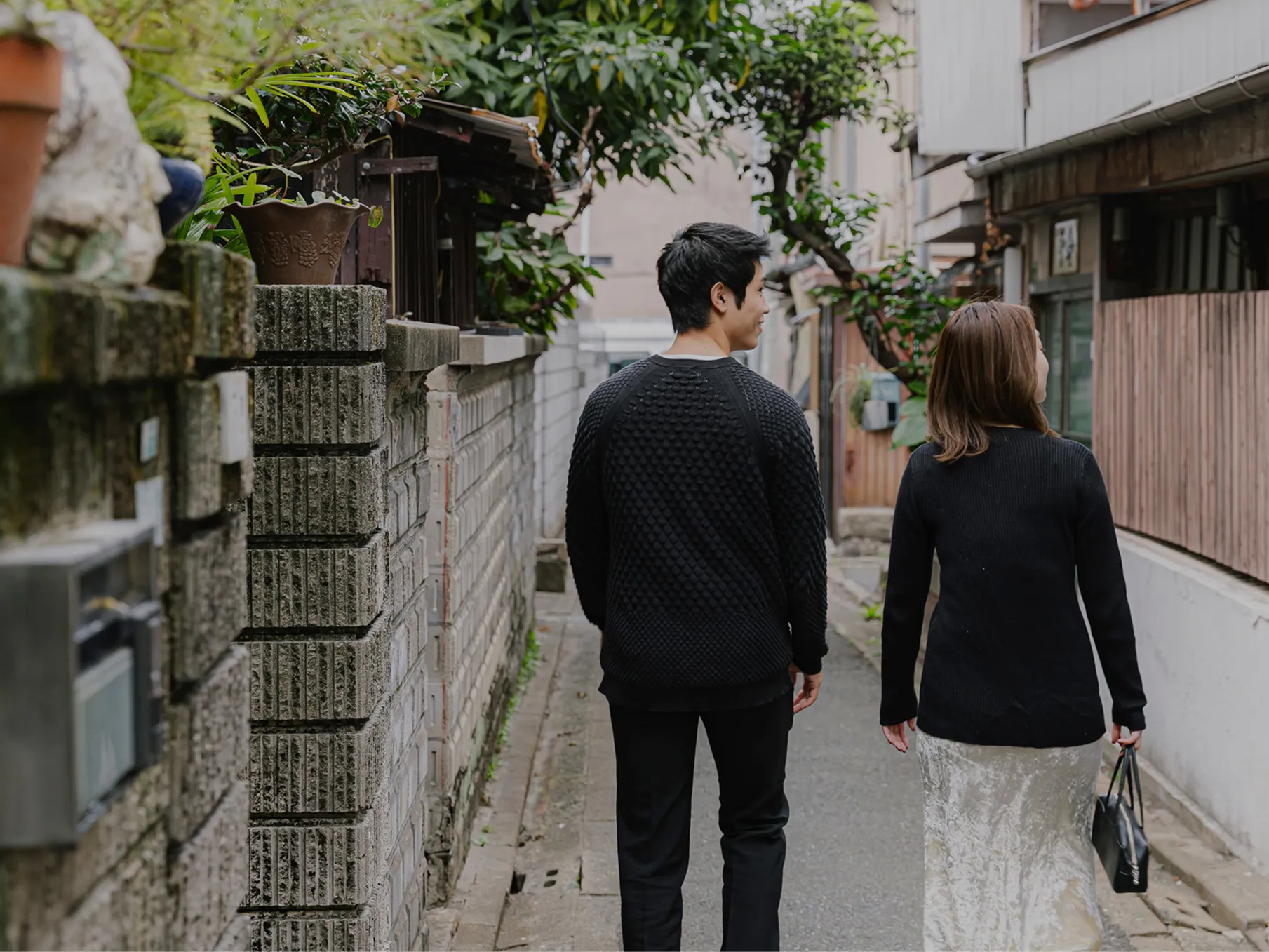 昔ながらの住宅街の小道を歩く男女2人