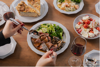 テーブルに並んだ料理を囲んで食事を楽しむ様子の写真