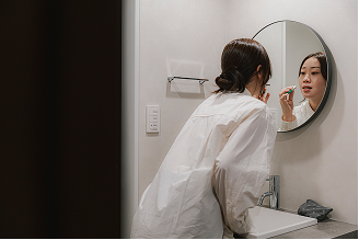 洗面台で鏡を見ながら身支度をする女性の写真