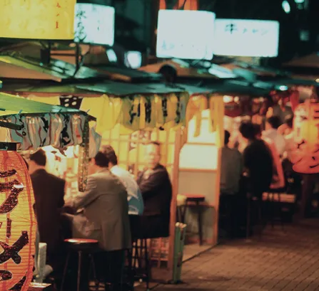 夜の屋台街で食事を楽しむ人々の様子。温かい照明に包まれた福岡の屋台風景。